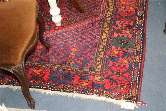 An Eastern red ground rug, woven with a central elongated hexagon 215cm x 135cm